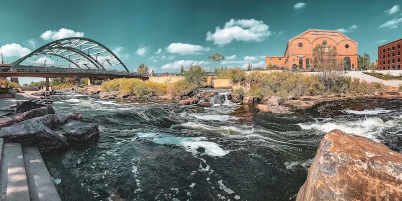 white water river with a bridge and a building in the background